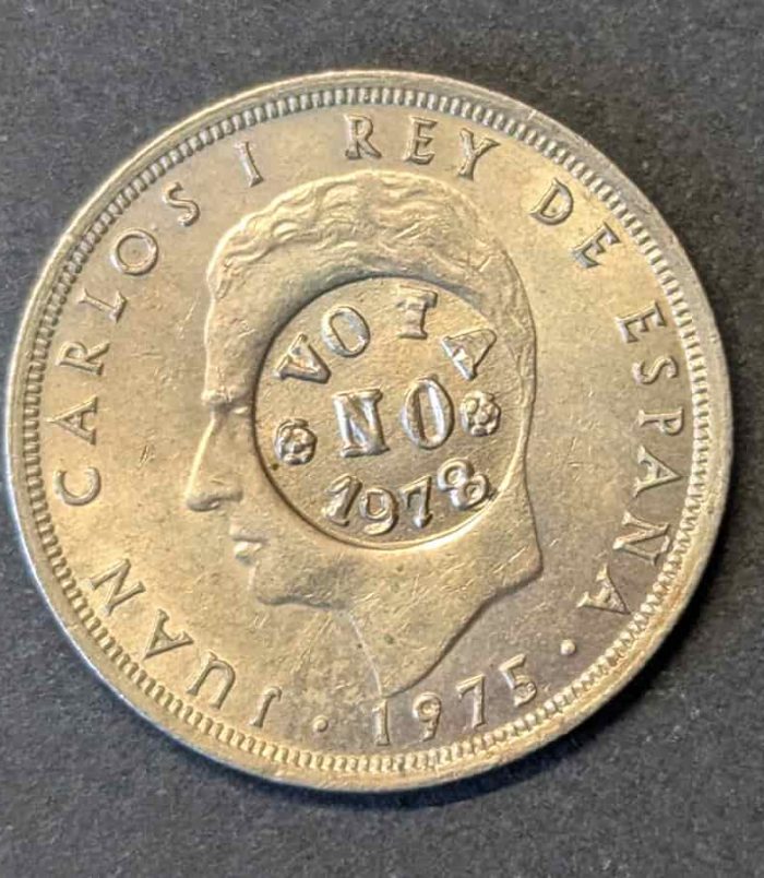 Escaso ejemplar de 25 pesetas de Juan Carlos I con la contramarca política "VOTA NO 1978". Una pieza de gran tamaño donde el resello del Referéndum Constitucional luce con total nitidez.